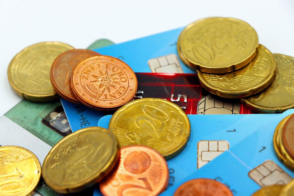 Imagem representando temas de finanças pessoais e gerenciamento de dinheiro, com moedas e cartões de crédito. 