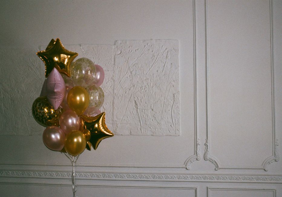 Balões decorativos em tons metálicos e rosa, usados como decoração para celebração ou festa em ambiente interno elegante.