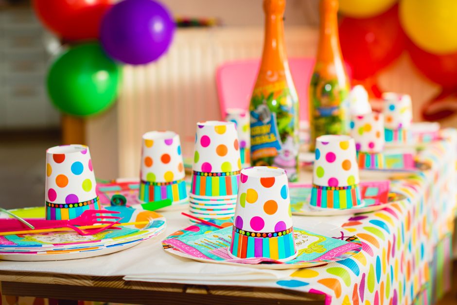 Mesa decorada para uma festa infantil, com copos, pratos e balões coloridos, criando um ambiente festivo e alegre.