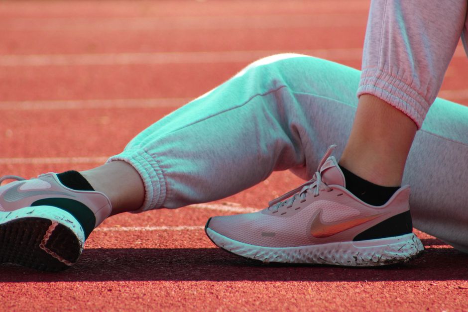 Pessoa se preparando para correr ou fazer exercícios em uma pista de atletismo, destacando atividade física e esporte.