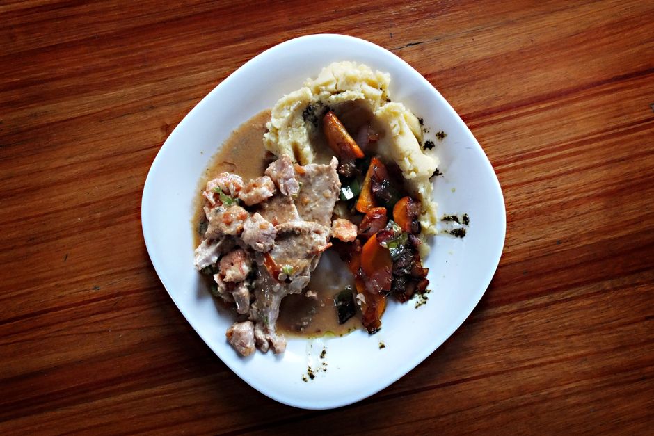Prato caseiro com carne, purê de batatas e legumes refogados, apresentado em um prato branco sobre uma mesa de madeira.