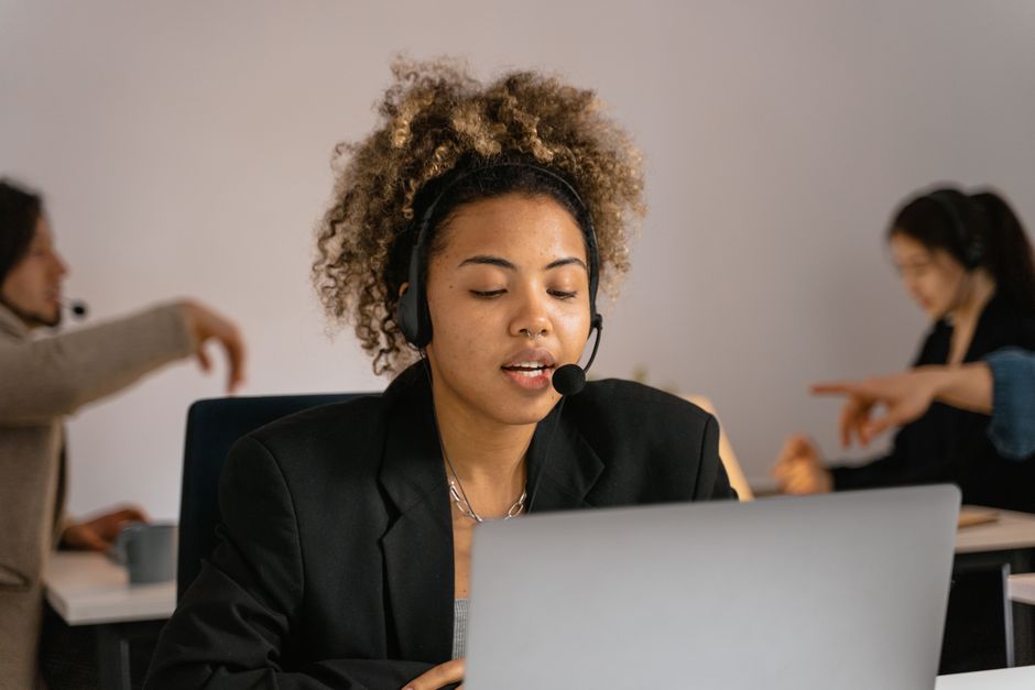 Mulher atendente de call center usando headset em ambiente de trabalho profissional.