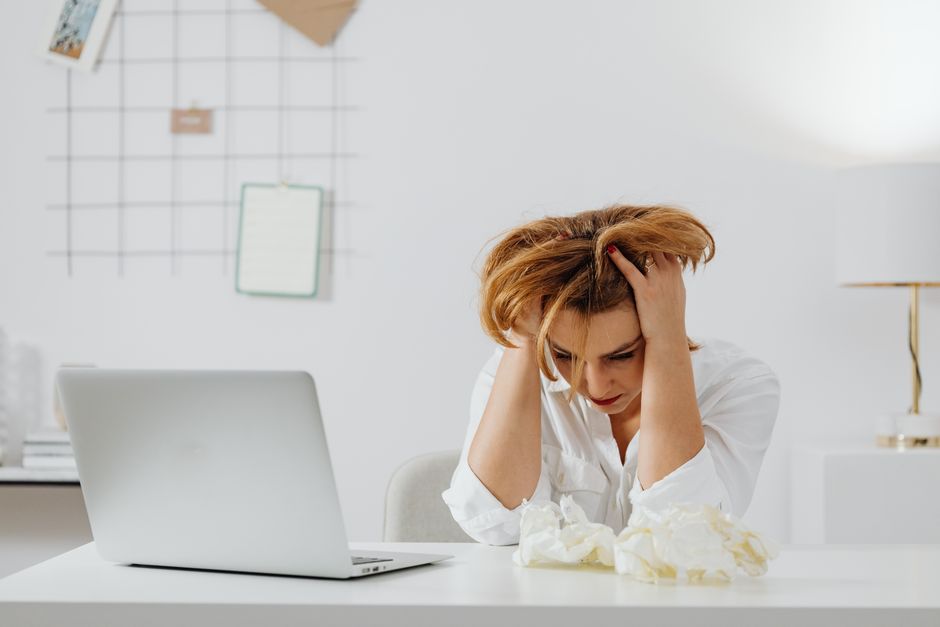 Mulher sobrecarregada e frustrada diante de problemas no ambiente de trabalho, evidenciando estresse e ansiedade.