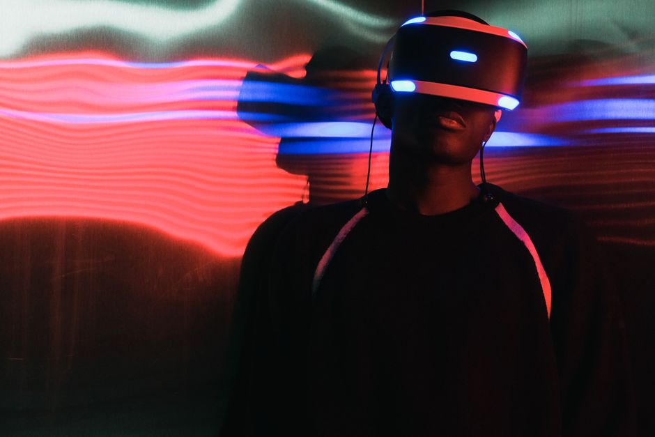 Pessoa usando óculos de realidade virtual em ambiente com iluminação de luzes coloridas, representando tecnologia e inovação.