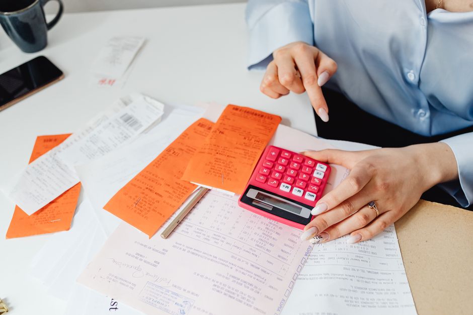Pessoa organizando e revisando contas e despesas, destacando a gestão financeira pessoal ou empresarial.