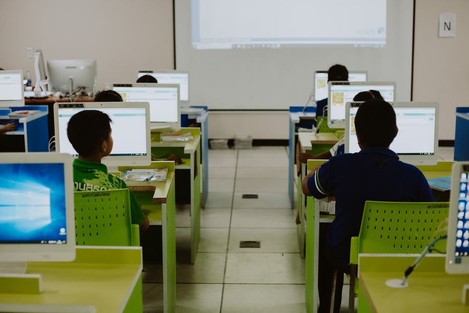 Sala de aula com estudantes utilizando computadores em um ambiente de ensino tecnológico.