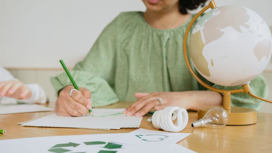 Imagem de uma criança estudando conceitos de sustentabilidade e meio ambiente, com elementos educativos e ecológicos ao redor.