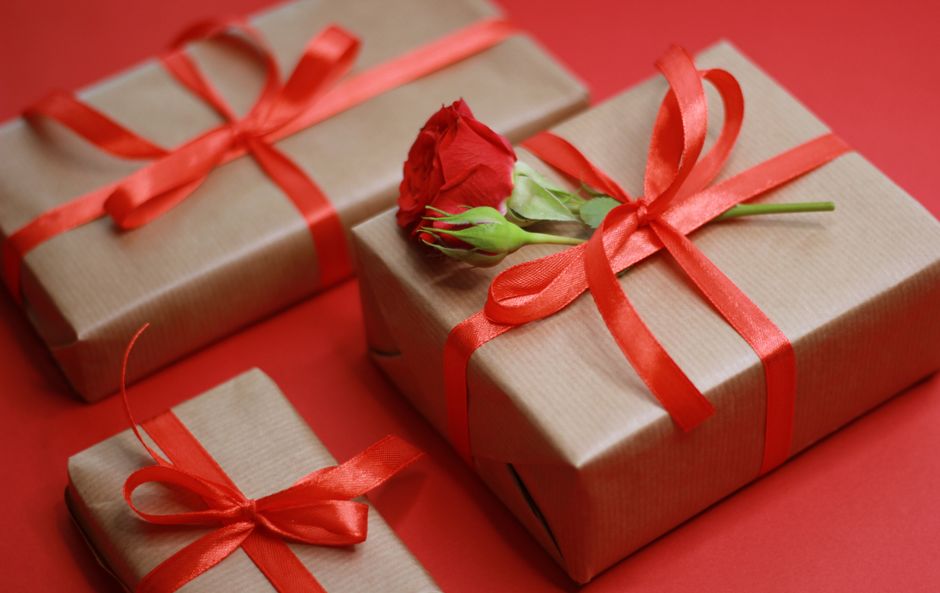 Presentes embrulhados com fita vermelha e uma rosa, simbolizando celebração ou ocasião especial.