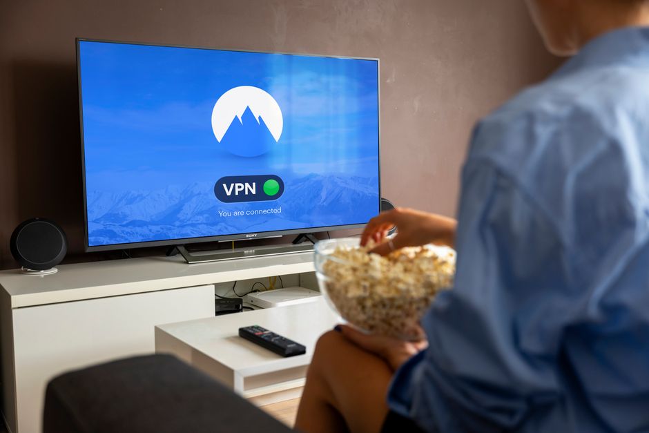 Pessoa assistindo TV enquanto segura uma tigela de pipoca, com foco no tema de entretenimento e lazer em casa.