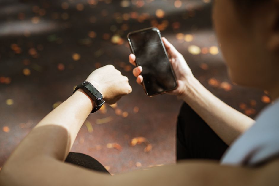 Pessoa verificando o horário e notificações no smartphone durante uma caminhada ao ar livre, representando gestão do tempo na rotina diária.