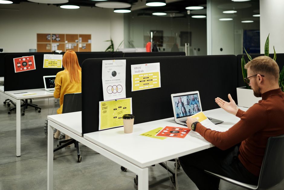 Ambiente de coworking com pessoas trabalhando em laptops e apresentando análises e estratégias de negócios.