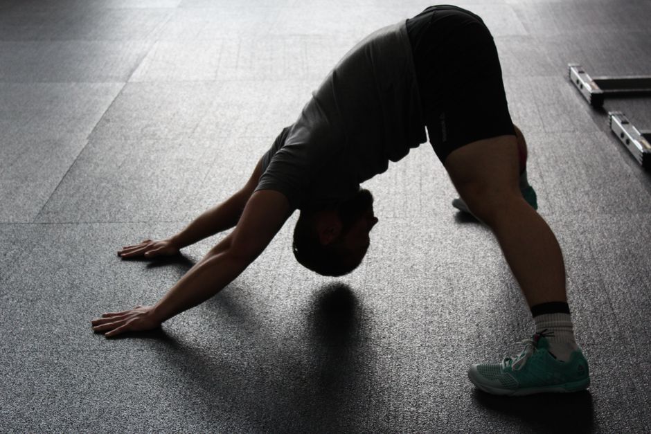 Pessoa praticando alongamento ou yoga em ambiente interno, focada em flexibilidade e bem-estar.