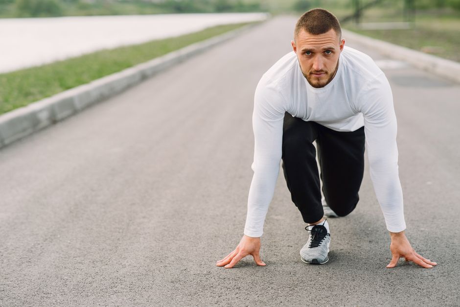 Homem na ponto de partida em uma corrida, simbolizando preparação e início de desafios.
