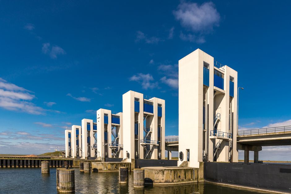 Imagem de uma usina hidrelétrica moderna localizada ao lado de um corpo de água, destacando sua arquitetura funcional e sustentável.