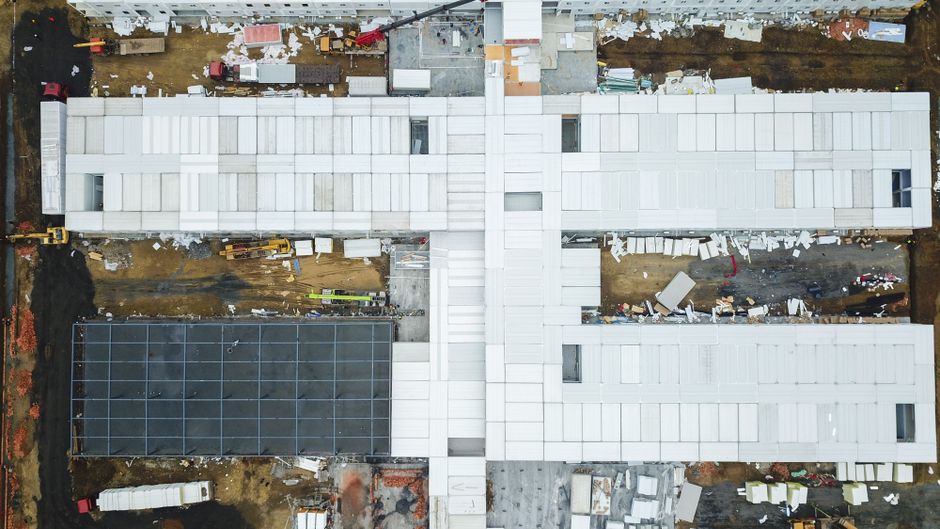 Visão aérea de uma construção em andamento, destacando o processo de edificação de uma estrutura modular.