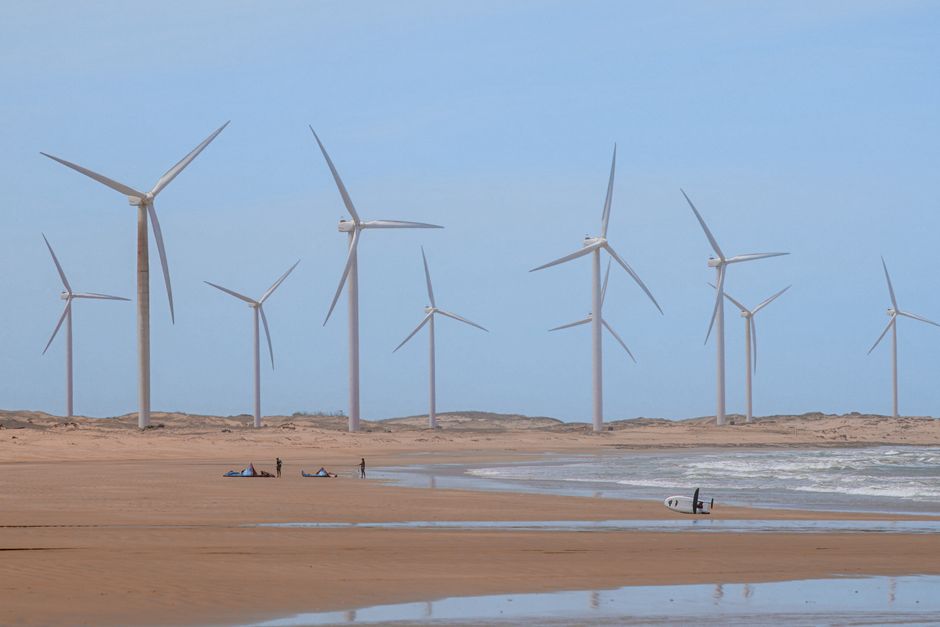 Painel de parques eólicos em uma praia, destacando fontes de energia renovável ao ar livre.