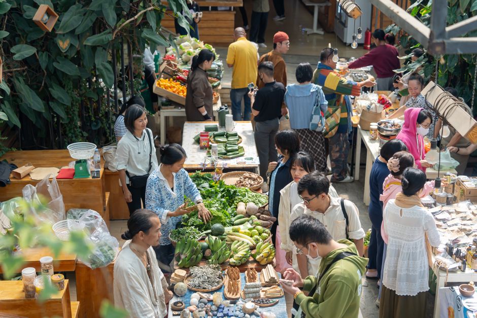 Pessoas fazendo compras em um mercado de feira livre com viés sustentável e orgânico, promovendo a economia local e a alimentação saudável.