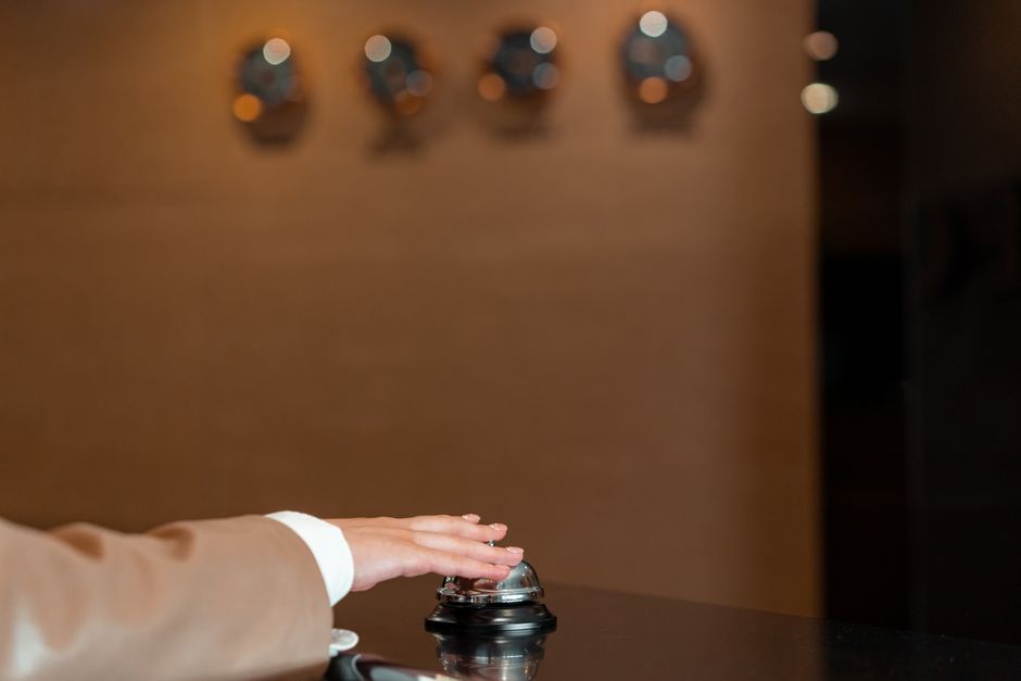 Pessoa pressionando um botão de recepção ou atendimento, simbolizando serviço ao cliente ou suporte no ambiente de negócios.