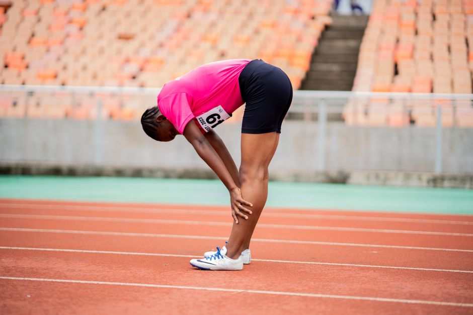 Atleta no estádio se preparando para a corrida, evidenciando esforço e concentração na preparação física.