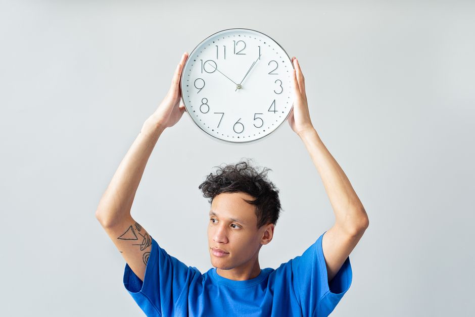 Homem segurando um relógio de parede simbolizando gerenciamento de tempo e produtividade.