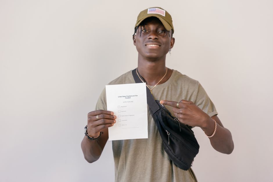 Jovem afrodescendente segurando um formulário de eleição presidencial, simbolizando participação política e engajamento cívico.
