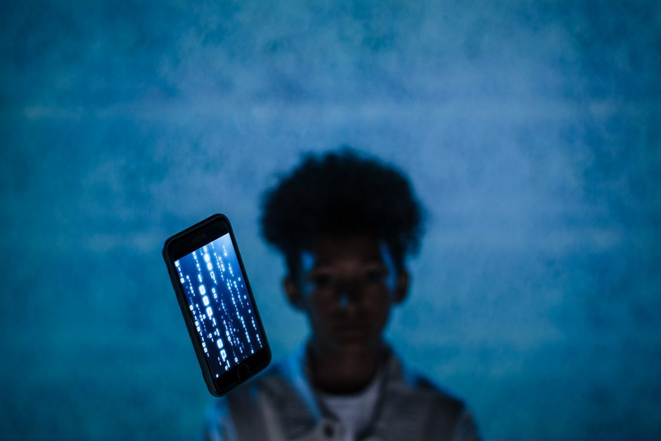 Pessoa segurando um smartphone com uma tela que exibe códigos binários, transmitindo um tema de tecnologia e inovação digital.