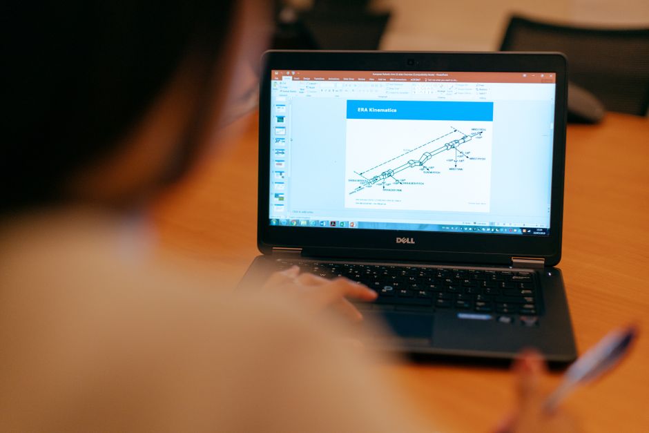 Pessoa acompanhando uma apresentação ou relatório técnico em um laptop, focada em gerenciamento de projetos ou análise de dados.