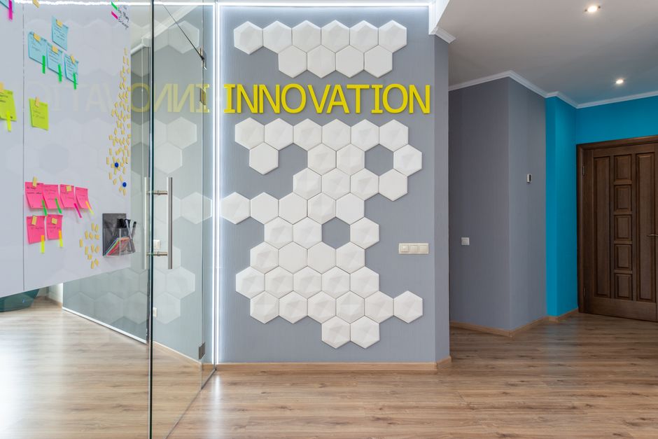 Espaço de trabalho moderno com foco em inovação, decorado com elementos hexagonais e painel de palavra motivacional.