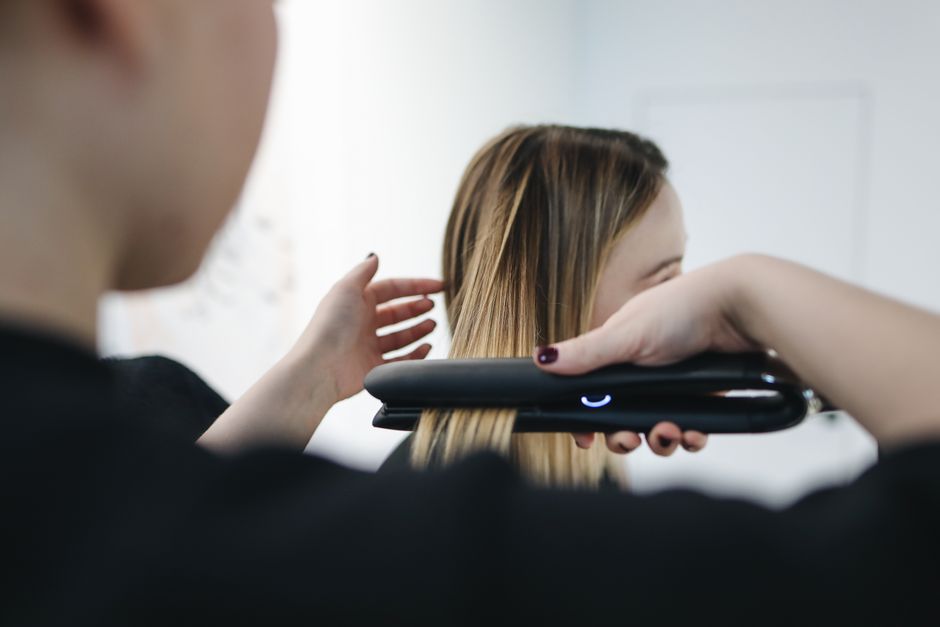 Pessoa preparando o cabelo usando uma prancha de alisar, com foco em estética e beleza.