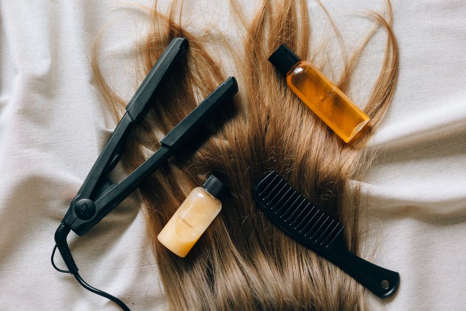 Imagem de cabelos longos com produtos de cuidados capilares e uma escova, simbolizando rotinas de beleza e cuidados pessoais.