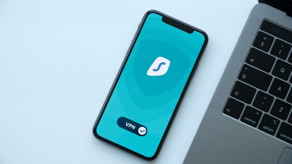 Imagem de um smartphone exibindo um aplicativo de VPN ao lado de um laptop, destacando segurança digital e proteção de dados.