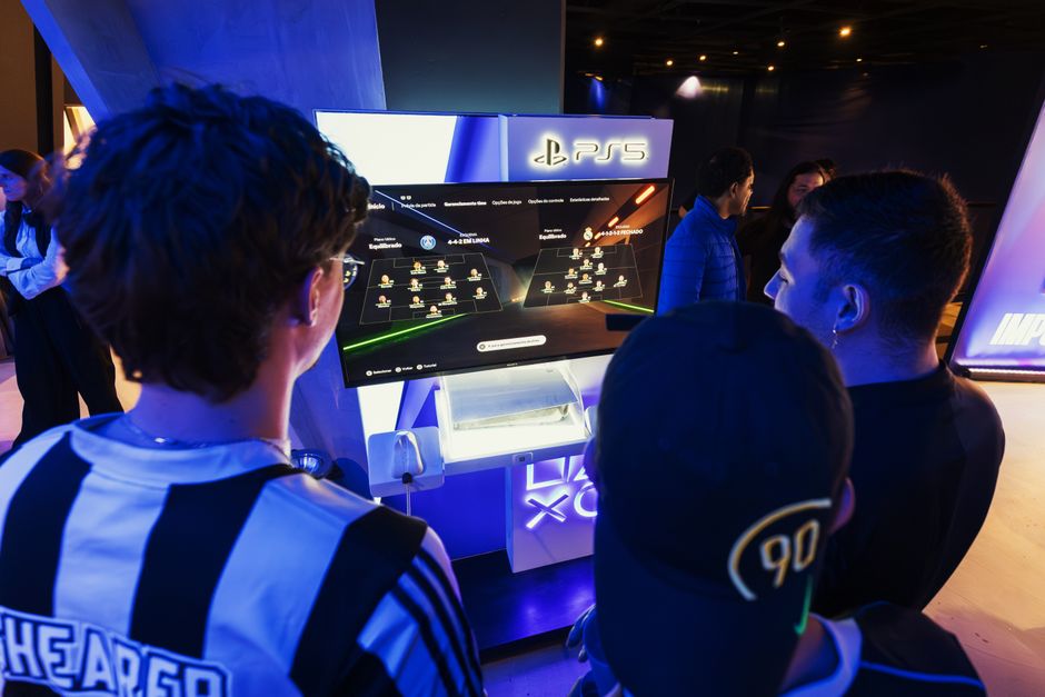 Grupo de jovens jogando videogame em um evento de lançamento de console, com foco na experiência de entretenimento digital.