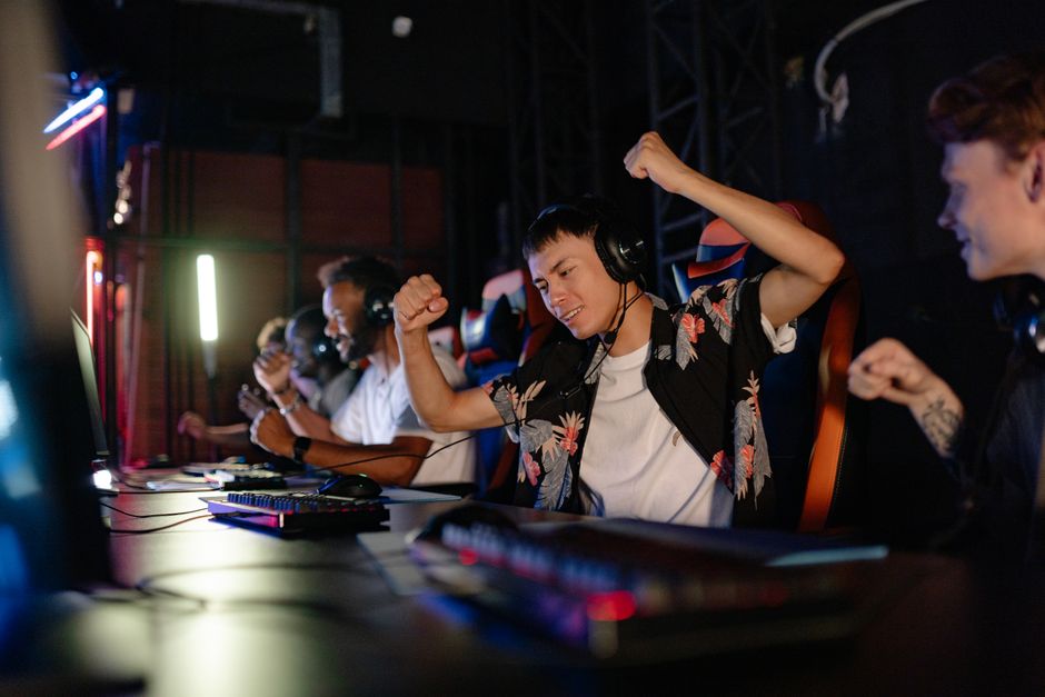 Grupo de jovens jogando videogame competitivo em um ambiente de eSports, celebrando uma vitória com entusiasmo.