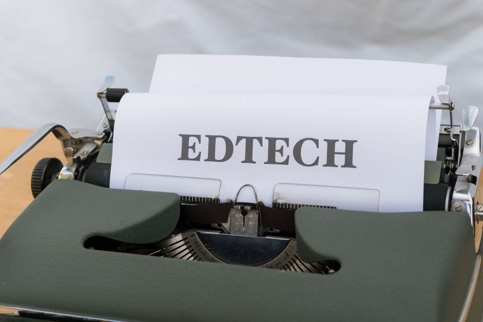 Máquina de escrever antiga com papel impresso com a palavra 'EDTECH', simbolizando a combinação de educação e tecnologia.