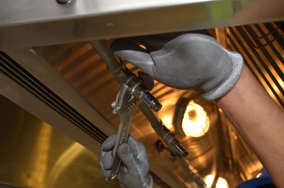 Imagem ilustrando um técnico ajustando um equipamento industrial ou de manutenção com uso de ferramentas em um ambiente de trabalho técnico.