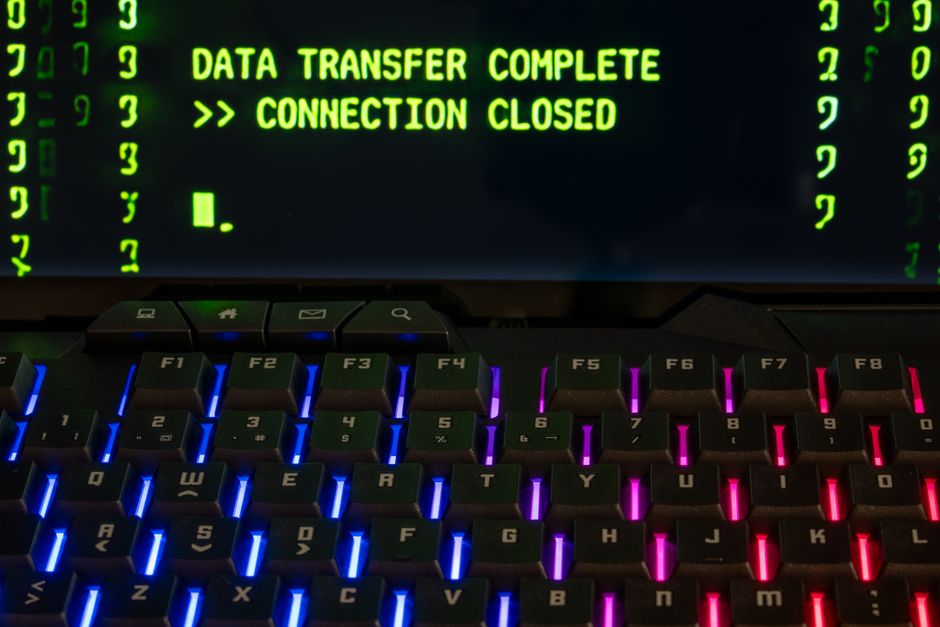 Tela de computador exibindo mensagem de confirmação de transferência de dados, com teclado iluminado em cores vibrantes, representando segurança na transferência de informações digitais.