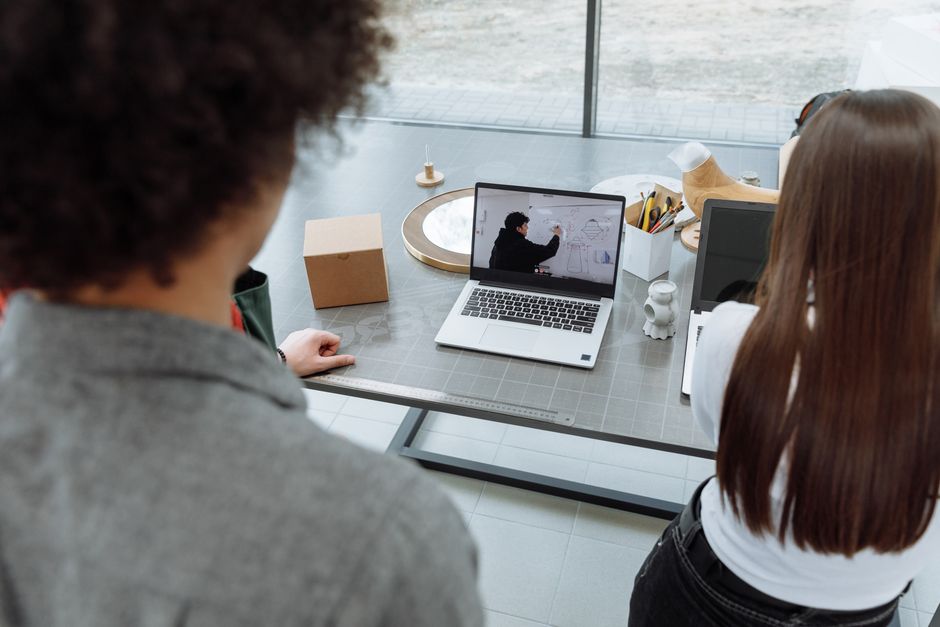 Imagem de duas pessoas observando uma apresentação de projeto ou conceito em um ambiente de coworking ou escritório criativo.
