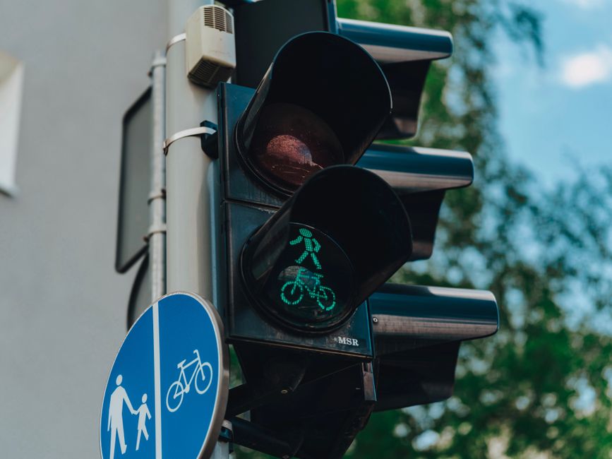 Semáforo com sinal verde para ciclistas e pedestres, indicando prioridade na travessia de bicicleta e caminhada.