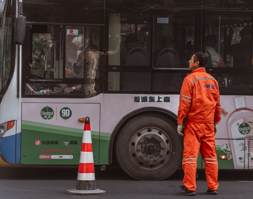 Profissional de limpeza urbano conversando com condutor de ônibus em uma via pública, destacando o tema de sustentabilidade e serviços urbanos.