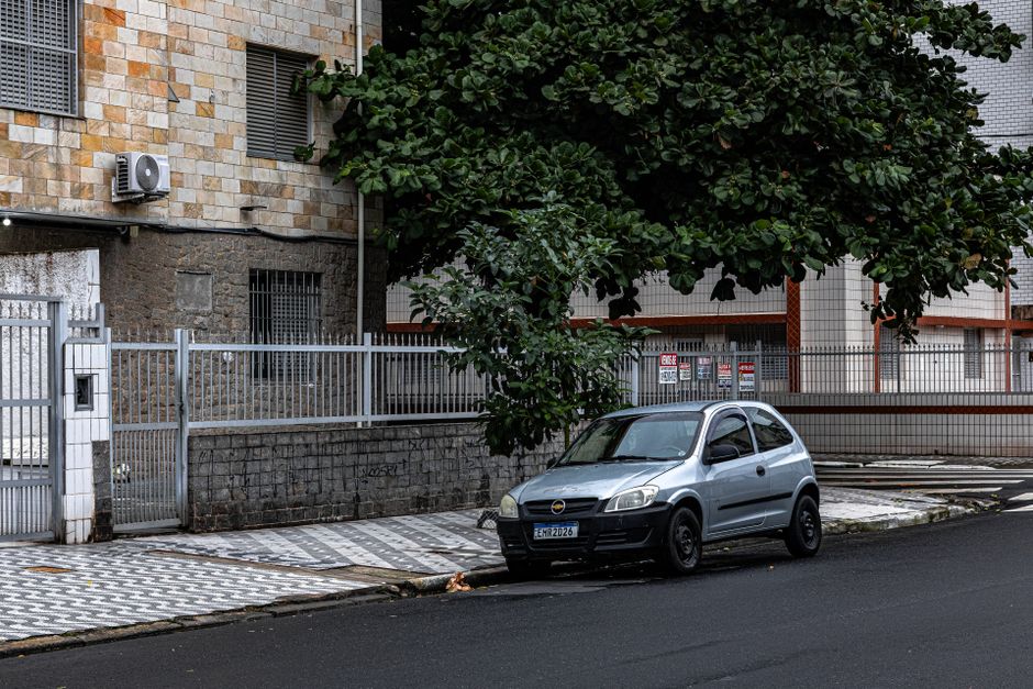Imagem de uma rua residencial com um carro estacionado e árvores, ilustrando o ambiente urbano e cotidiano.