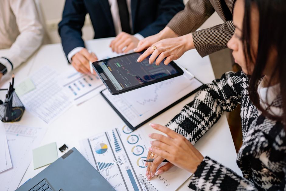 Reunião de equipe analisando dados financeiros e gráficos em um ambiente de escritório.