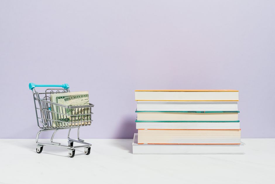 Imagem representando planejamento financeiro e organização de recursos, com carrinho de compras cheio de dinheiro ao lado de uma pilha de livros.