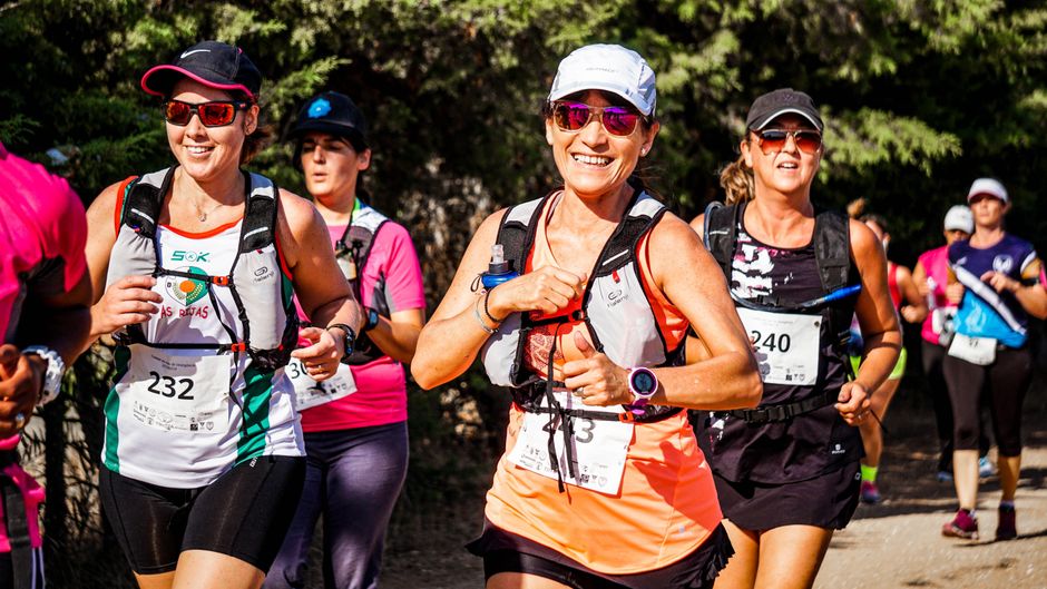 Grupo de mulheres participantes de uma corrida de aventura, sorrindo e desfrutando a experiência ao ar livre.