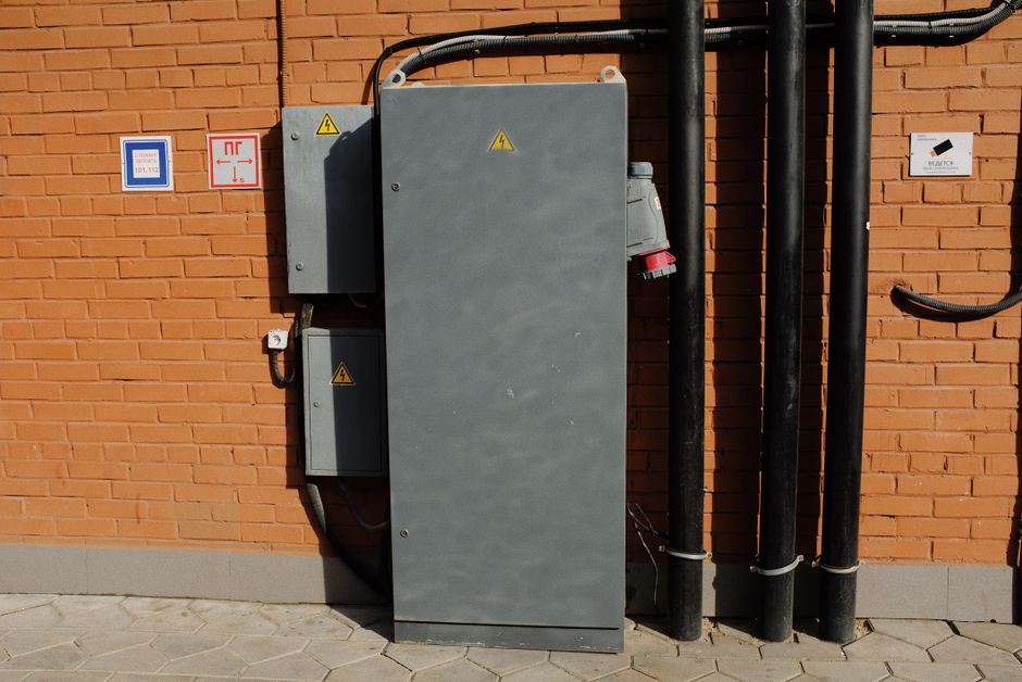 Imagem de uma instalação elétrica externa em uma parede de tijolos, destacando infraestrutura de energia industrial ou comercial.