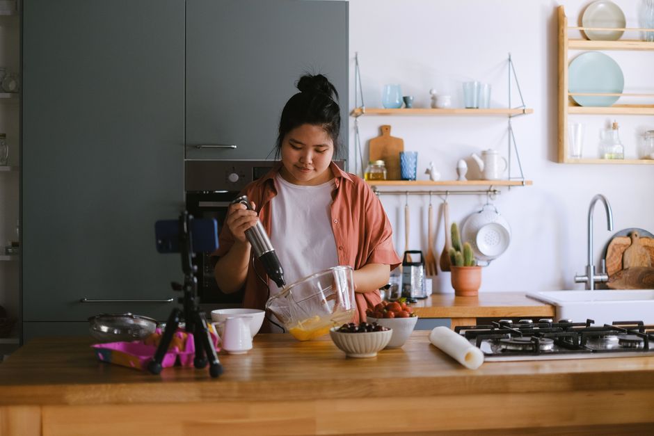 Mulher preparando um vídeo de culinária para blog em uma cozinha moderna e bem iluminada.