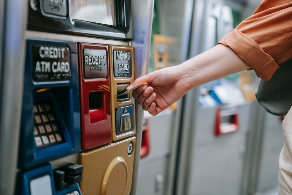 Pessoa usando cartão em máquina de pagamento, ilustrando o ato de realizar transações financeiras com cartão de crédito ou débito.
