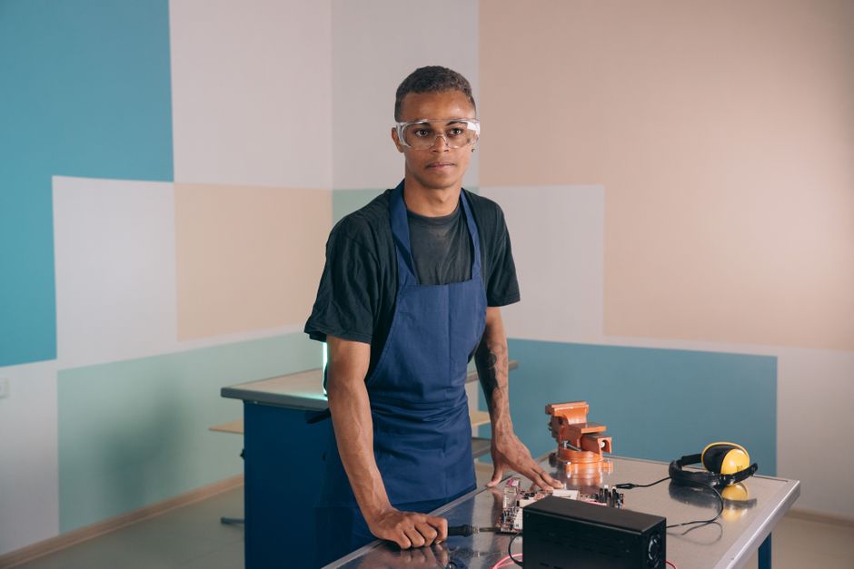 Jovem profissional em ambiente de laboratório ou oficina, demonstrando foco em tecnologia e inovação.