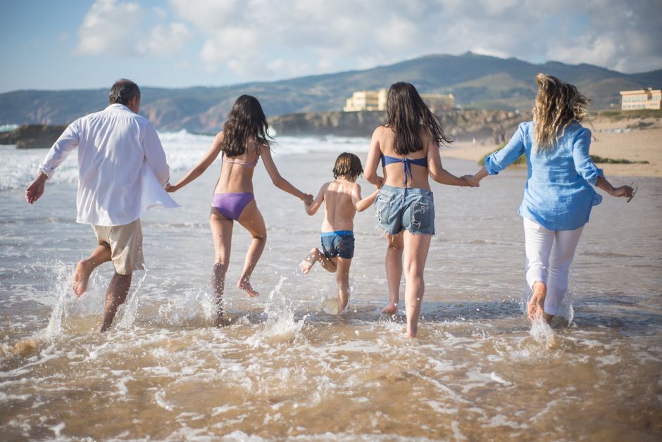 Família brincando e se divertindo na praia, aproveitando um dia de lazer com energia e alegria ao lado do mar.