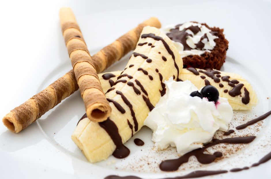 Sobremesa de sobremesa, com bananas, sorvete, chantilly, bolo de chocolate e biscoitos, exibida de forma apetitosa e decorativa.