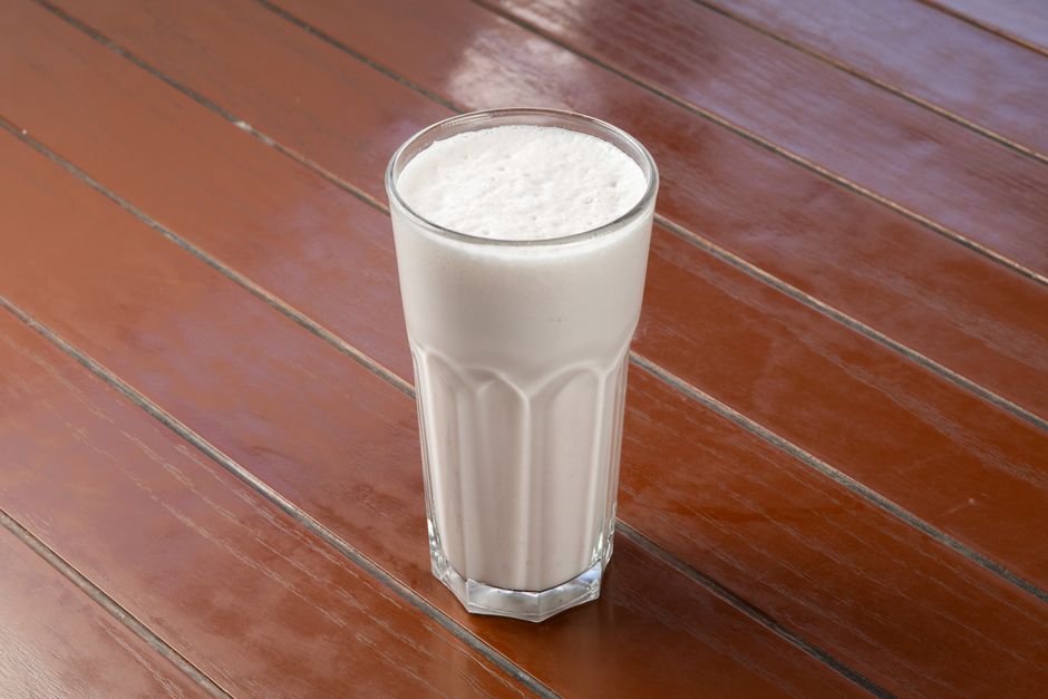 Imagem de um copo com leite colocado sobre uma superfície de madeira, representando alimentação saudável e nutrição.